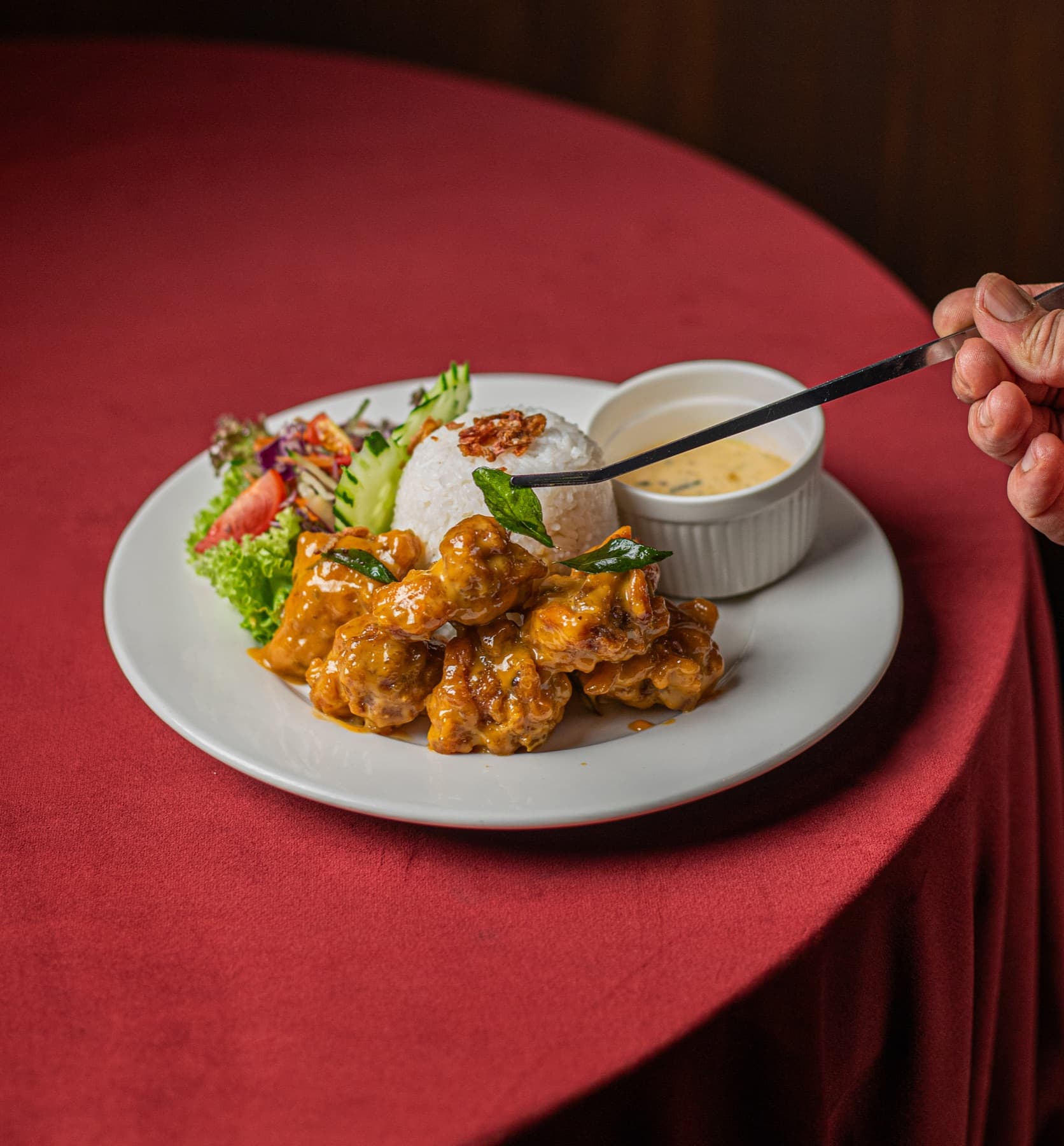 JIBRIL Salted Egg Butter Chicken with rice, salad and sauce on a red tablecloth.