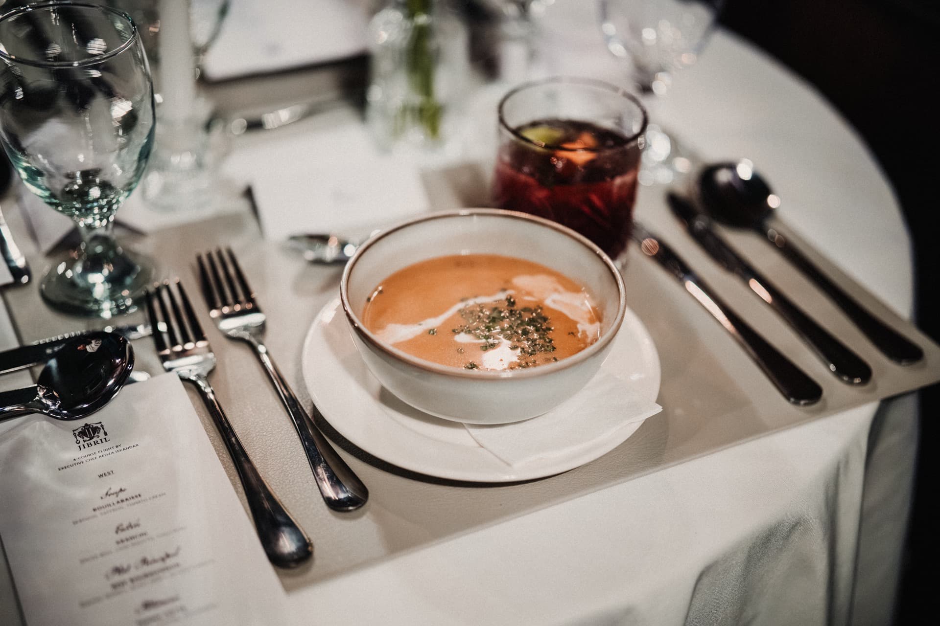A set dinner table at JIBRIL with soup, mocktail and menu card.